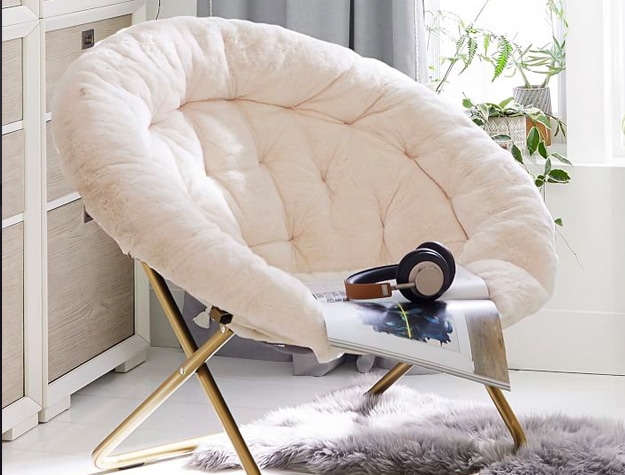 Magazine and headphones sitting on a Polar Bear Faux-Fur Ivory Hang-a-Round Chair.