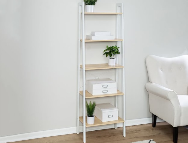 White ladder bookcase with plants and storage boxes.
