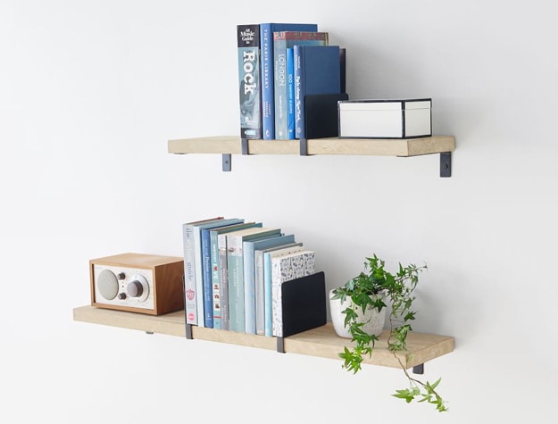 Natural wood floating shelves with books.