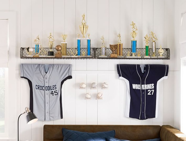 Floating shelving system with trophies and sports jerseys.