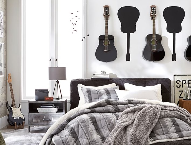 Guitars hanging above a bed.