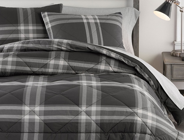 A black and white plaid comforter lays on top of a bed.