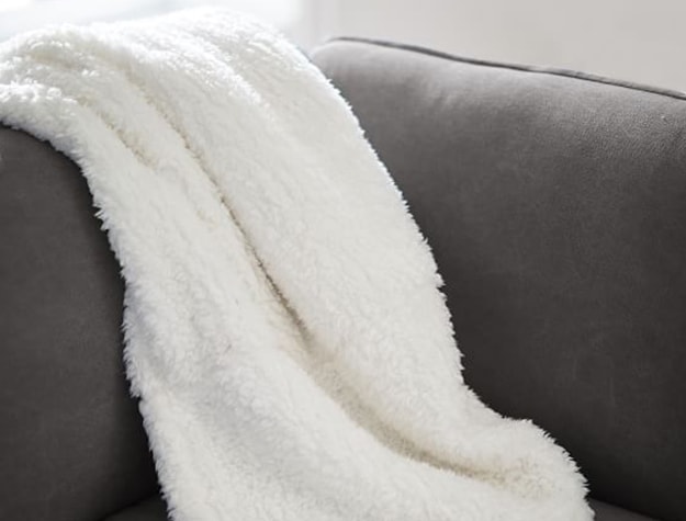 A white sherpa blanket drapes over a couch.