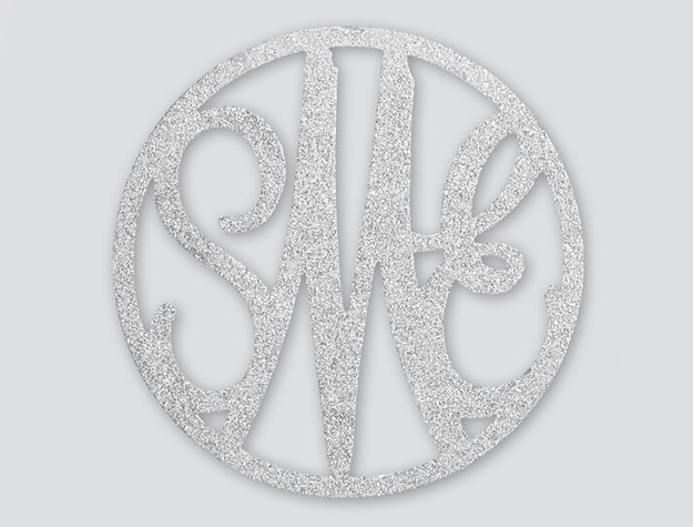 A glittered monogram wall decor rests against a white background.