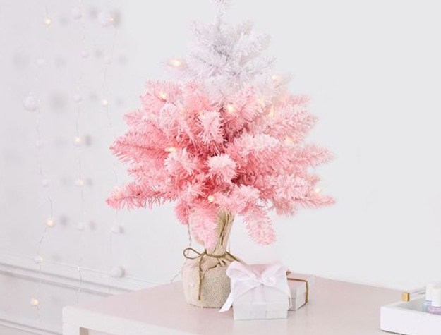 A mini ombre pink tree sits on a desk.