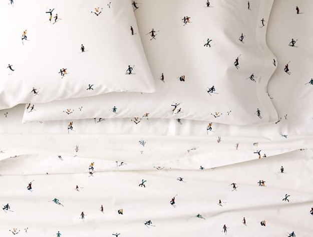 A sheet set covered in skiers adorns a bed.