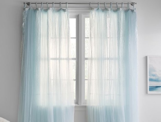 Sheer light blue curtains hang in a window.