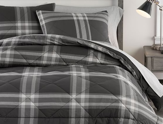 A black and white plaid bed comforter lays on a bed.