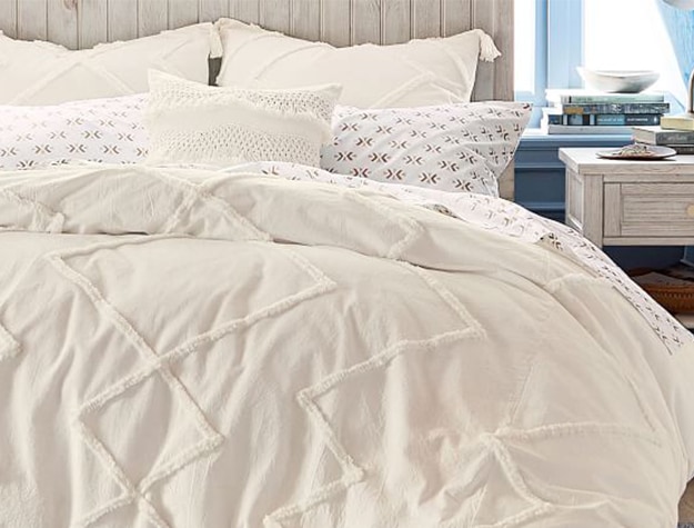 A textured cream bedspread covers a bed.
