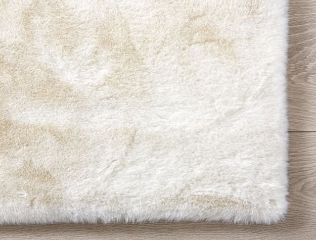 A white fur rug lays on a wooden floor.