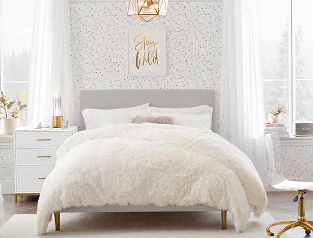 A bedroom features winter-inspired decor like a fluffy white bedspread.