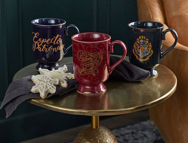 Three Harry Potter mugs sit on a golden tabletop.