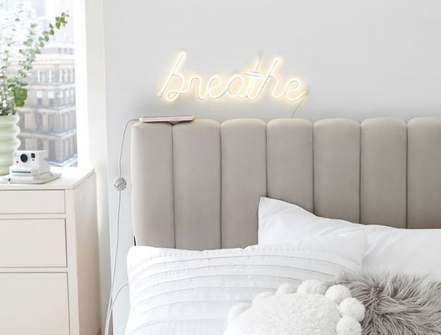 This channeled no-nails headboard is accented with a neon sign above it