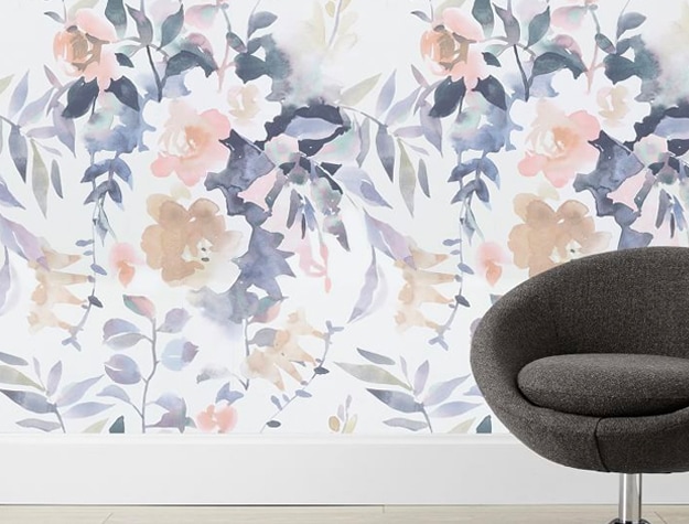 A gray chair next to a wall with Watercolor Floral Peel & Stick Wallpaper.