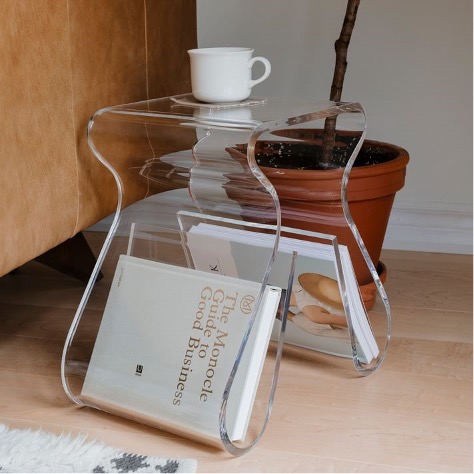A clear acrylic side table provides extra storage for books in its legs.
