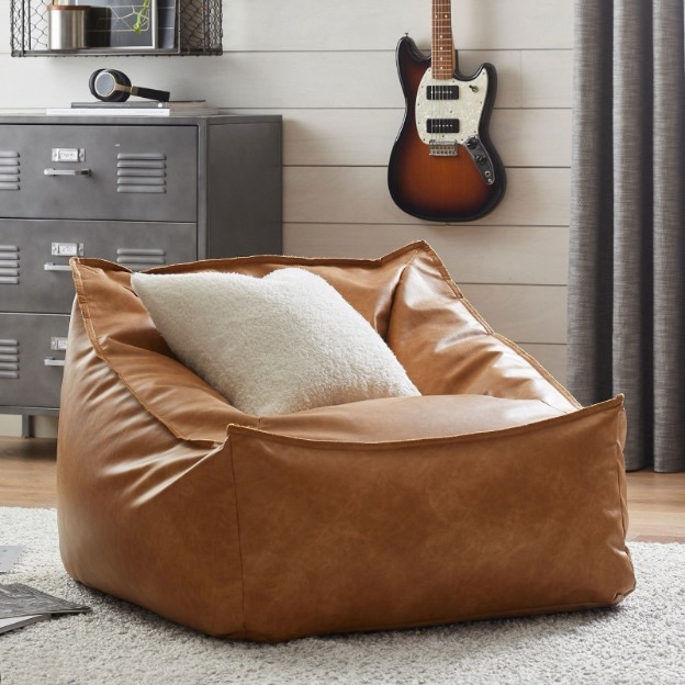 A caramel brown faux leather lounge chair is set in a boy’s bedroom