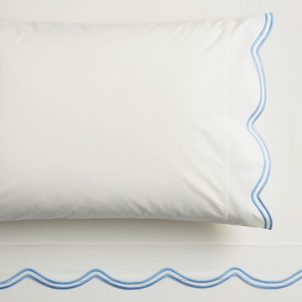 A detailed look at the LoveShackFancy blue embroidered scallop-edged organic sheet set.
