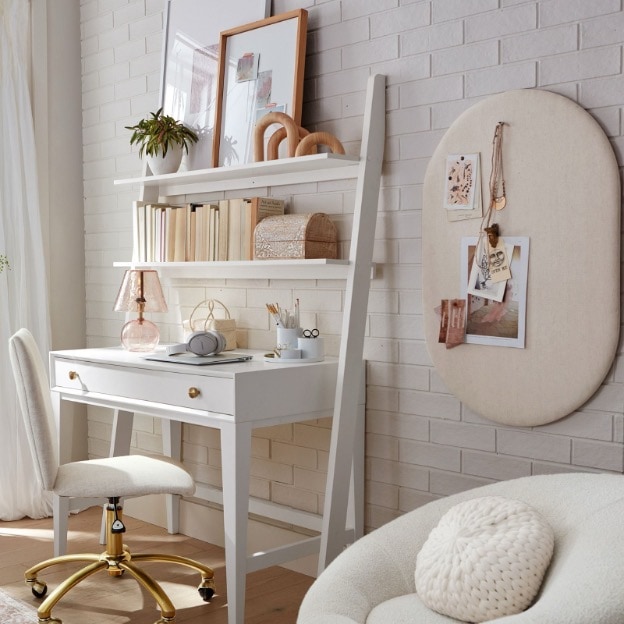 A no-nails pinboard shown in a dorm room next to a wall desk and desk chair