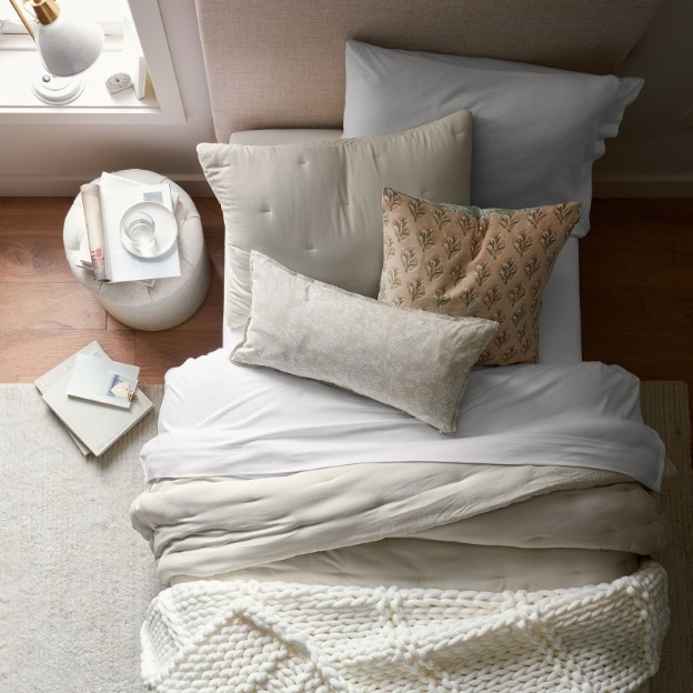 An overhead shot of a dorm bed piled high with decorative pillows