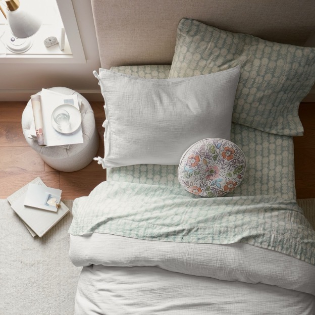 Overhead shot of a styled dorm bed, complete with sheets, duvet, and pillows