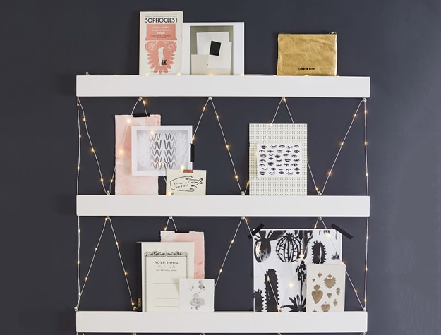 White shelves on dark wall with photos and cards