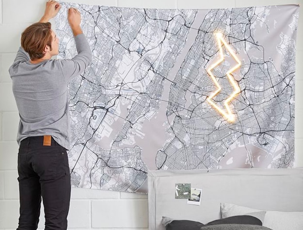 Teen boy putting up tapestry of Manhattan map Teen boy putting up tapestry of Manhattan map